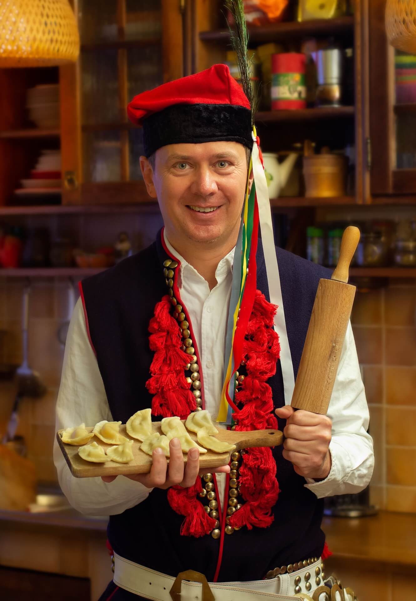 Tomasz Klimek, founder of Krakow Urban Tours, dressed in traditional Polish attire and holding homemade pierogi.
